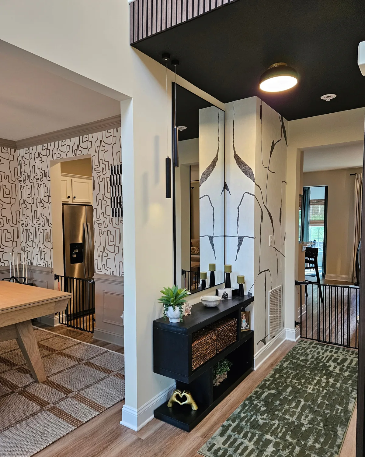 Hallway with a black ceiling, a black console with greenery, a tall mirror and a green runner leading toward the kitchen