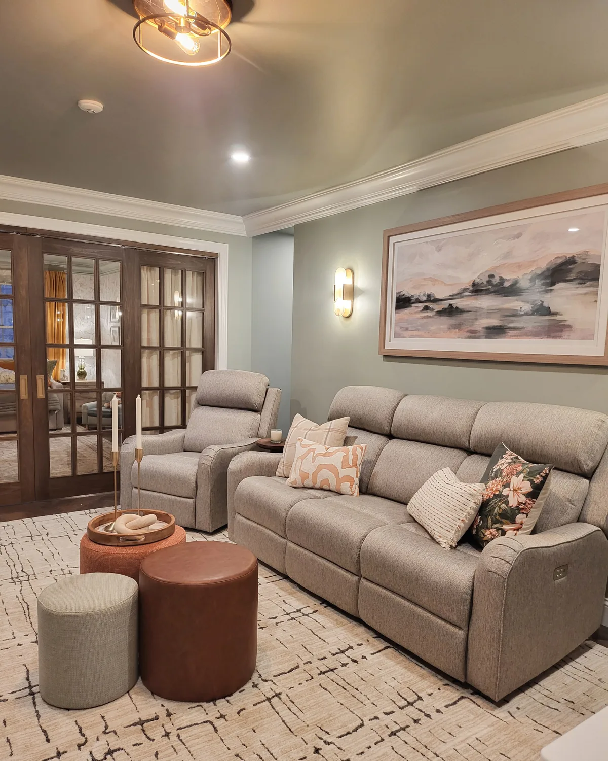 Bonus room lounge with gray power recliners, leather and fabric ottomans, a landscape painting and French doors