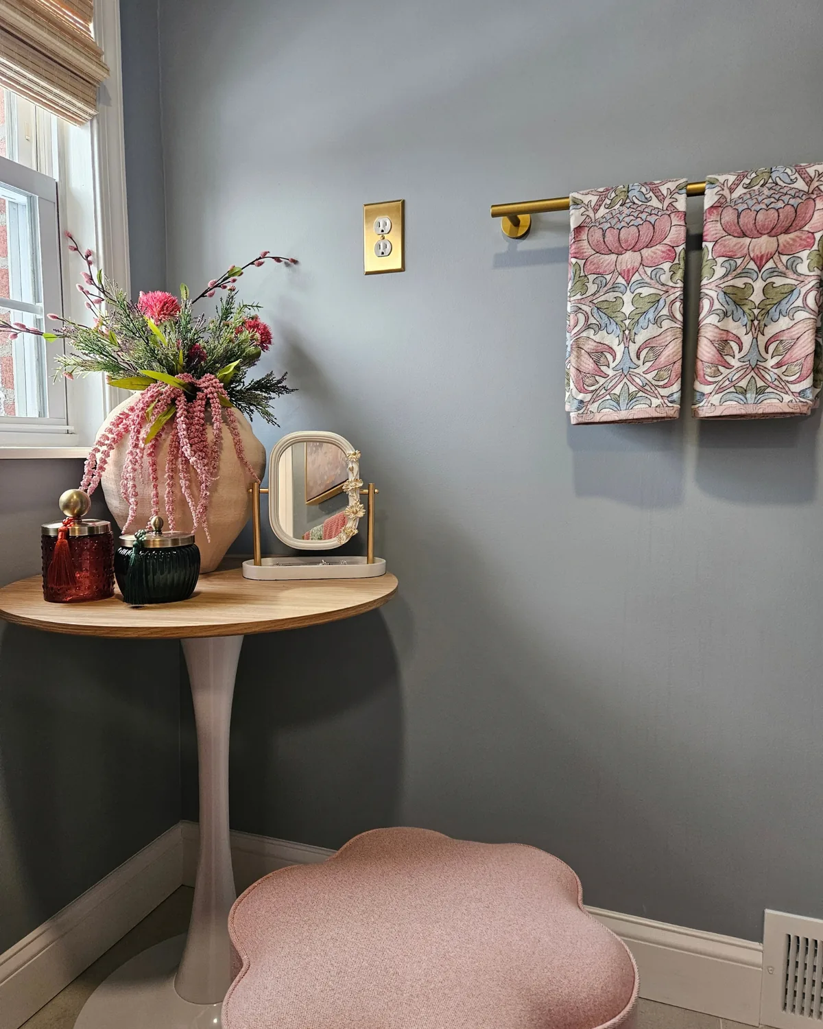 Bath corner with a white tulip table, a vase of pink amaranthus, a vanity mirror and a pink flower-shaped stool