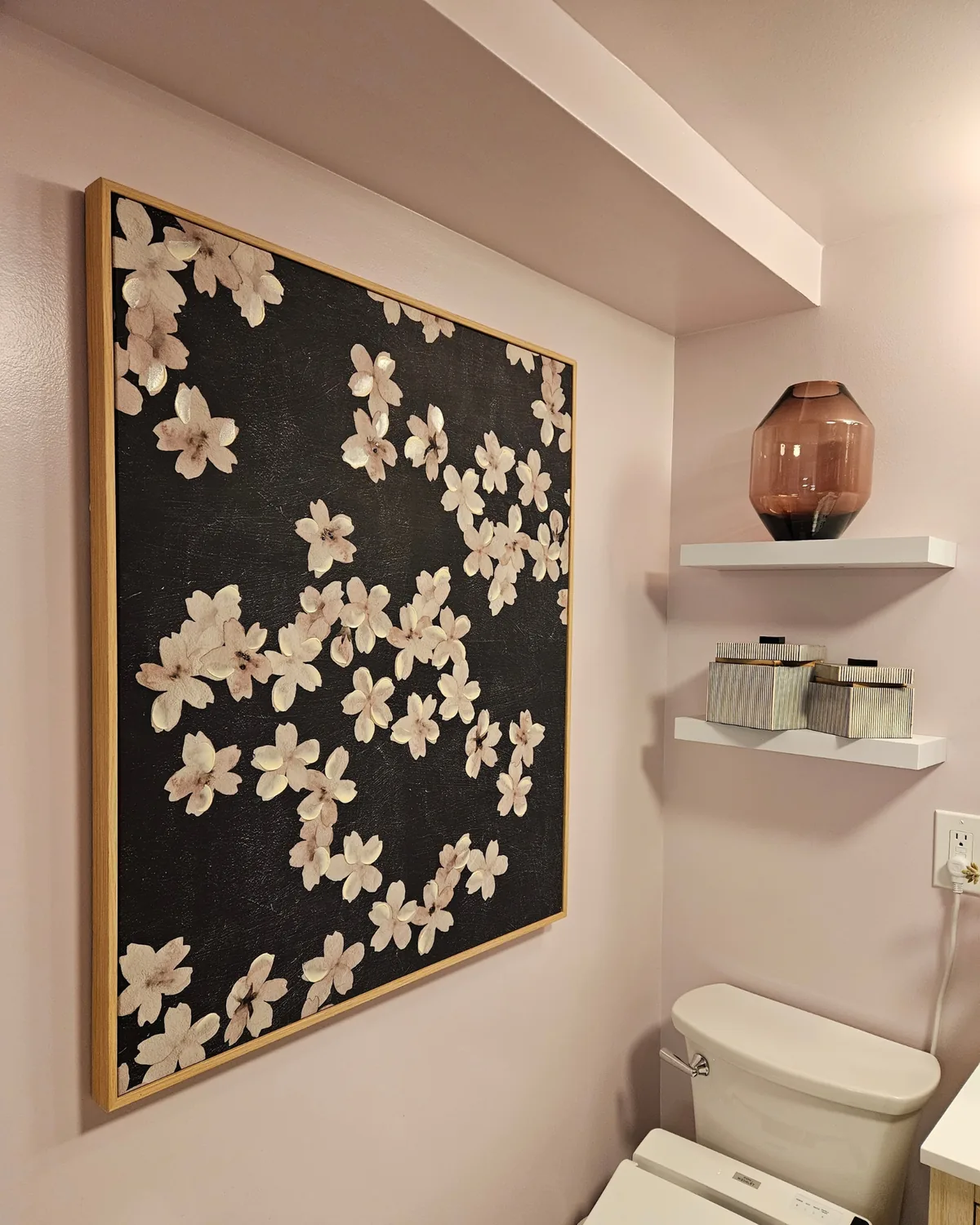 Blush bathroom with a large cherry-blossom painting, floating shelves and a plum glass vase