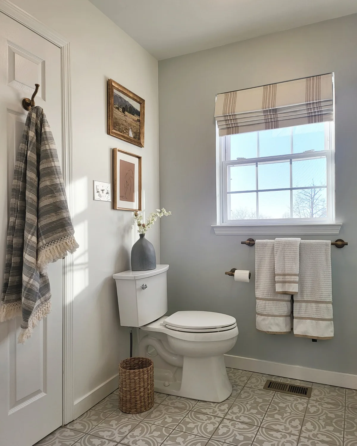 Powder room with blue-gray walls, a patterned tile floor, a striped Roman shade and plaid hand towels