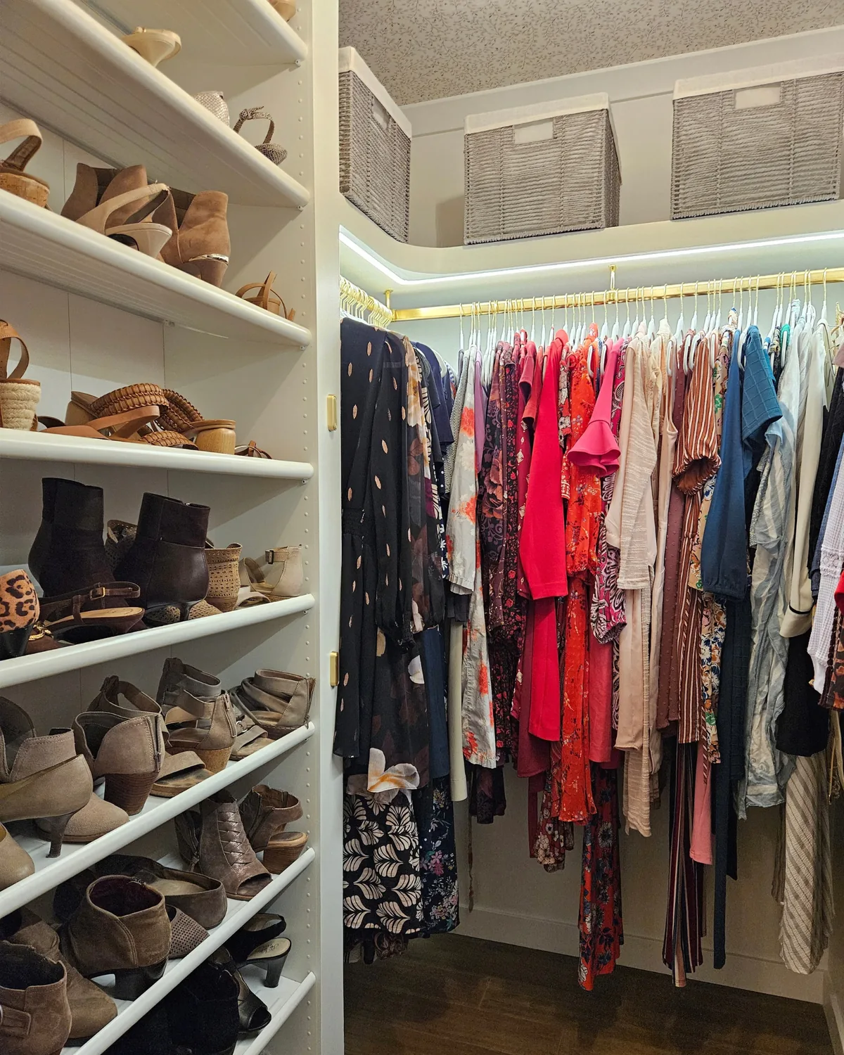 Walk-in closet with white shoe shelves, brass rods, LED-lit upper shelves and striped storage bins